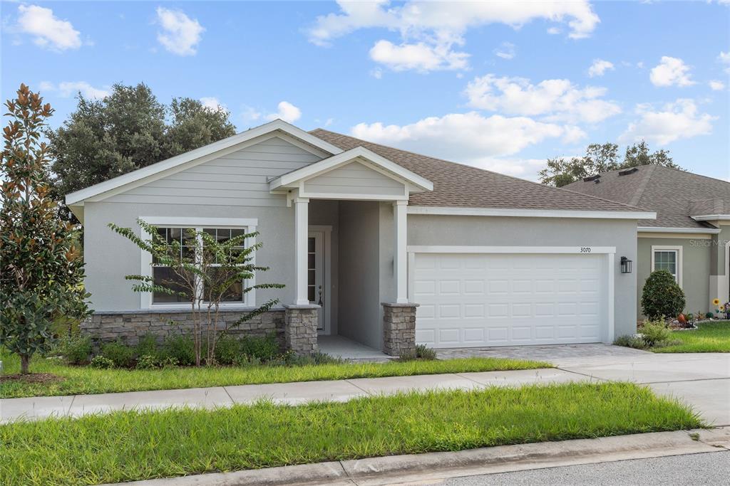 A single-story house with a gray stucco exterior, stone accents, and a two-car garage — 3070 SUNSCAPE TERRACE, GROVELAND, FL