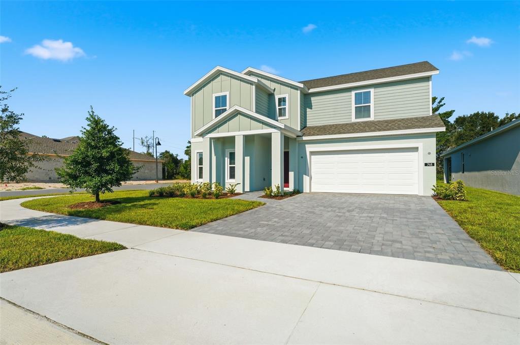 A two-story house with light green siding, a white garage, and a paved driveway — 748 FARFIELDS STREET, DELAND, FL