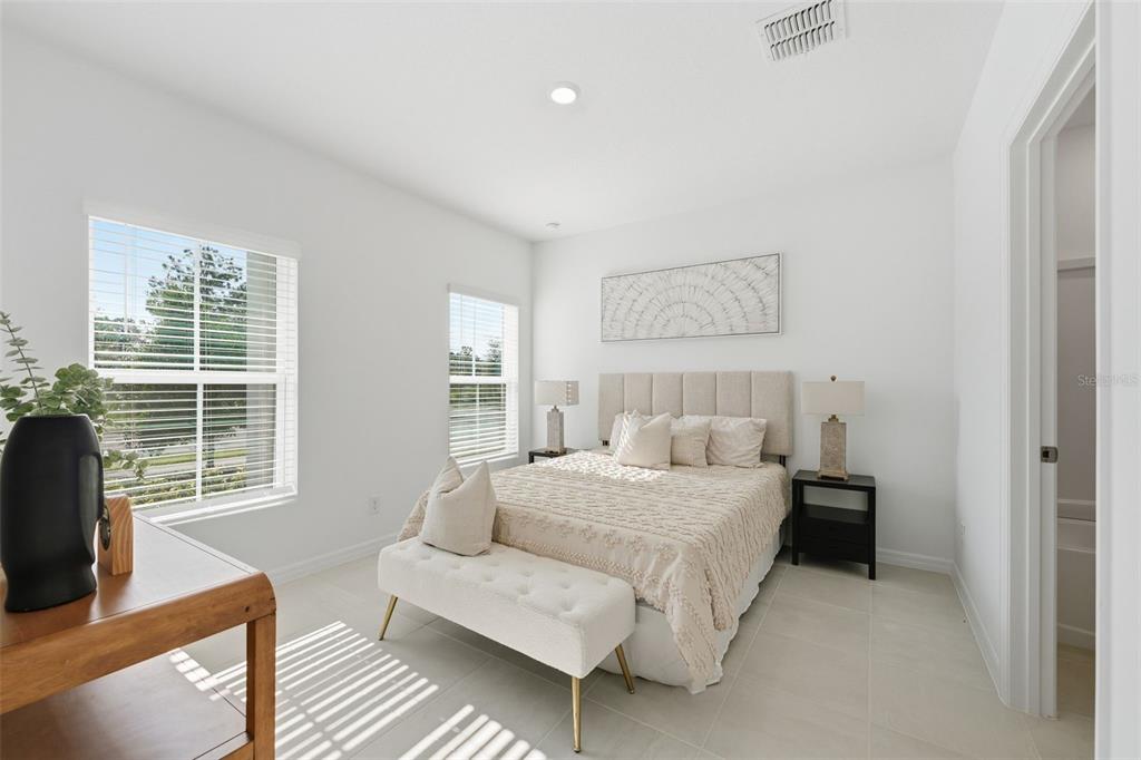 A bright bedroom features a bed with a tufted bench, two windows, and tile flooring — 748 FARFIELDS STREET, DELAND, FL