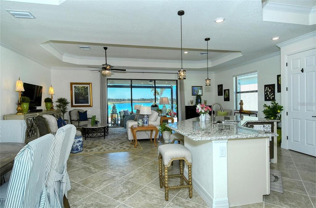 An open-concept kitchen and living area features granite countertops, tile flooring, and a lake view — 6132 CESSNA RUN, BRADENTON, FL