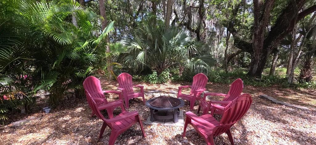 A fire pit surrounded by five red Adirondack chairs sits on a gravel patio — 400 LONGHORN DRIVE, RIVER RANCH, FL