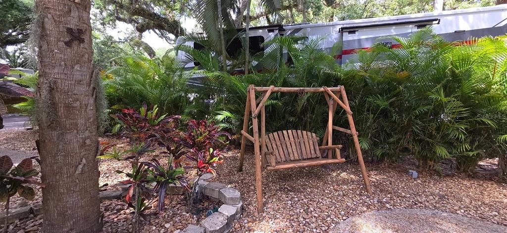 A wooden swing sits on a gravel yard in front of palm trees and a camper — 400 LONGHORN DRIVE, RIVER RANCH, FL