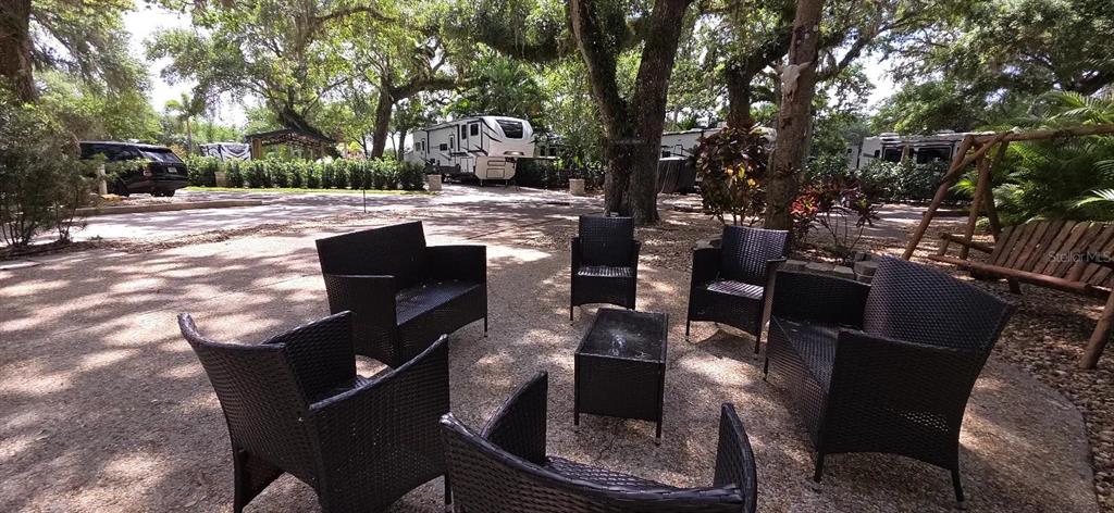 An outdoor patio area features wicker furniture arranged around a small table under large trees — 400 LONGHORN DRIVE, RIVER RANCH, FL