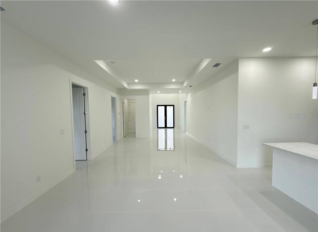 A bright, minimalist room features white walls, glossy tile flooring, and a tray ceiling — 4322 KISMET PARKWAY W, CAPE CORAL, FL