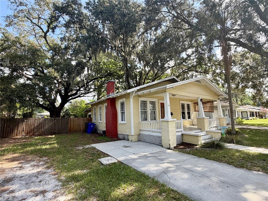 A yellow, single-story house with a red brick chimney and a front porch — 521 YOUNG PLACE, LAKELAND, FL