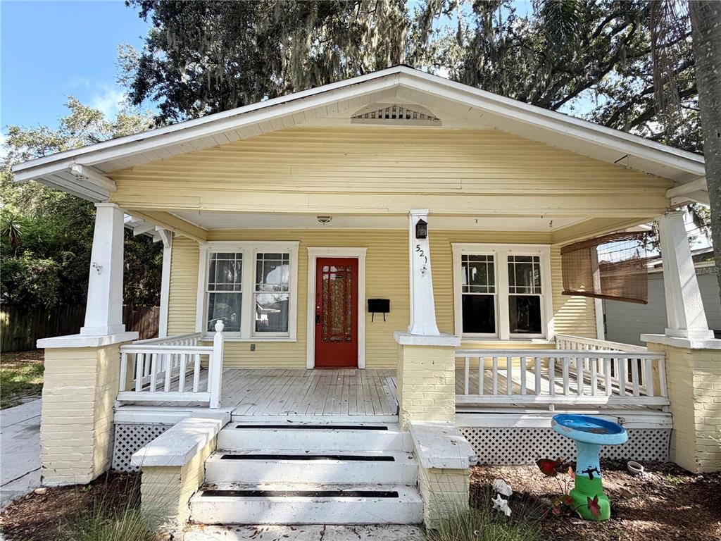 A yellow house with a front porch, white railings, and a red front door — 521 YOUNG PLACE, LAKELAND, FL