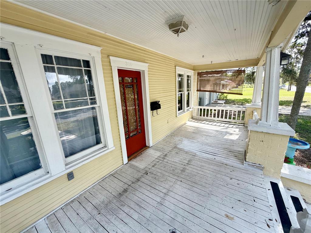 A covered front porch features yellow siding, a red front door, and white wooden decking — 521 YOUNG PLACE, LAKELAND, FL