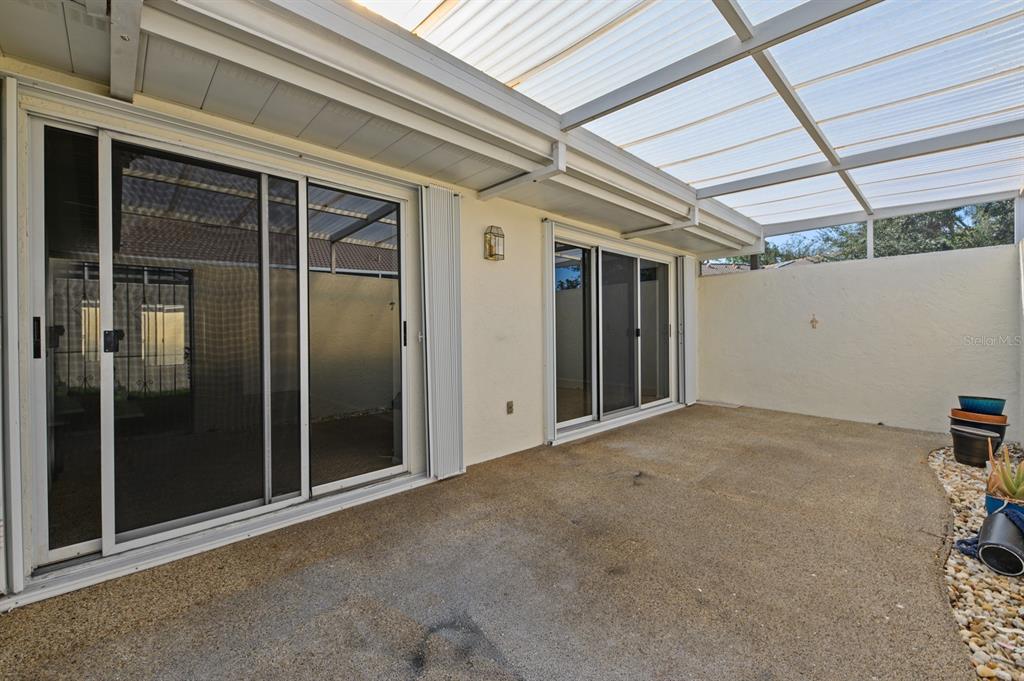A covered concrete patio features two sliding glass doors and a translucent roof panel — 5528 37TH STREET E UNIT 5528, BRADENTON, FL