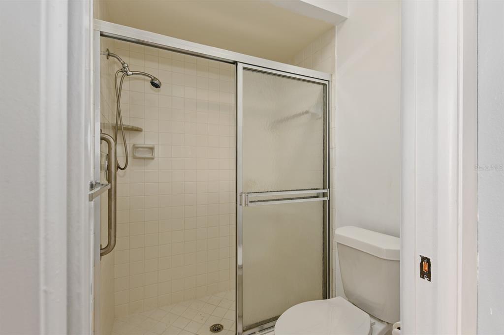 A bathroom features a tiled walk-in shower with a sliding glass door and a toilet — 5528 37TH STREET E UNIT 5528, BRADENTON, FL
