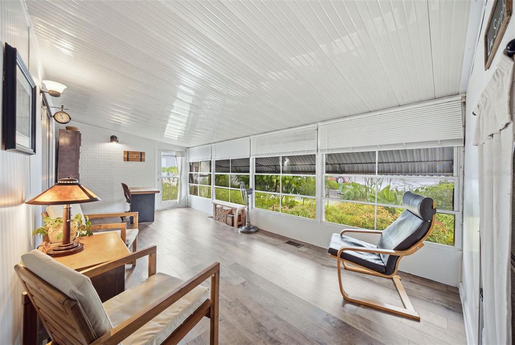 A sunroom with wood-look flooring, white paneled ceiling, large windows, and several chairs — 2215 73RD STREET E UNIT 162, PALMETTO, FL