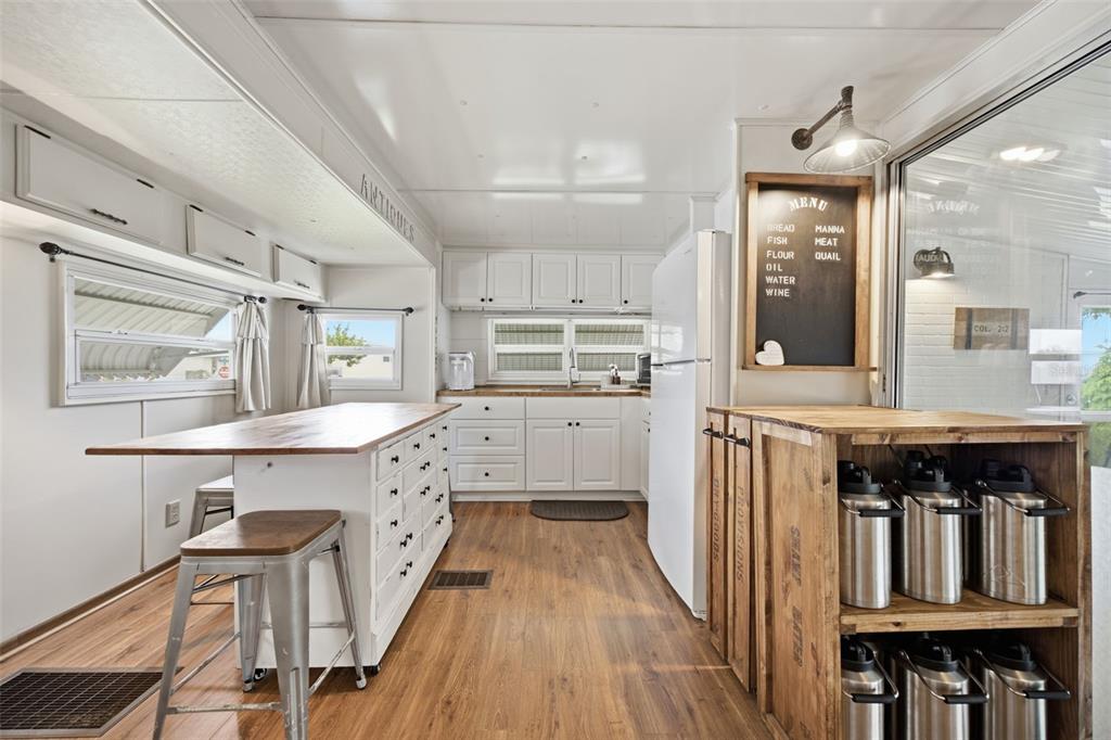 A kitchen features white cabinets, a wooden island with drawers, and a rustic menu board — 2215 73RD STREET E UNIT 162, PALMETTO, FL