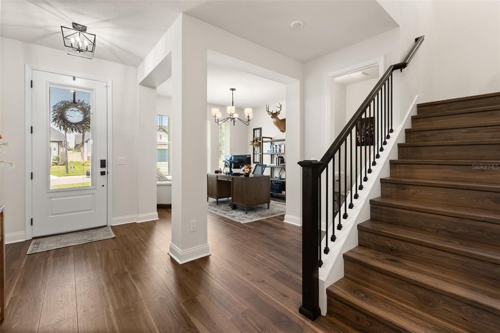 A bright entryway features wood-look flooring, a staircase with dark railings, and an adjacent office — 16974 CEDAR VALLEY CIRCLE, CLERMONT, FL