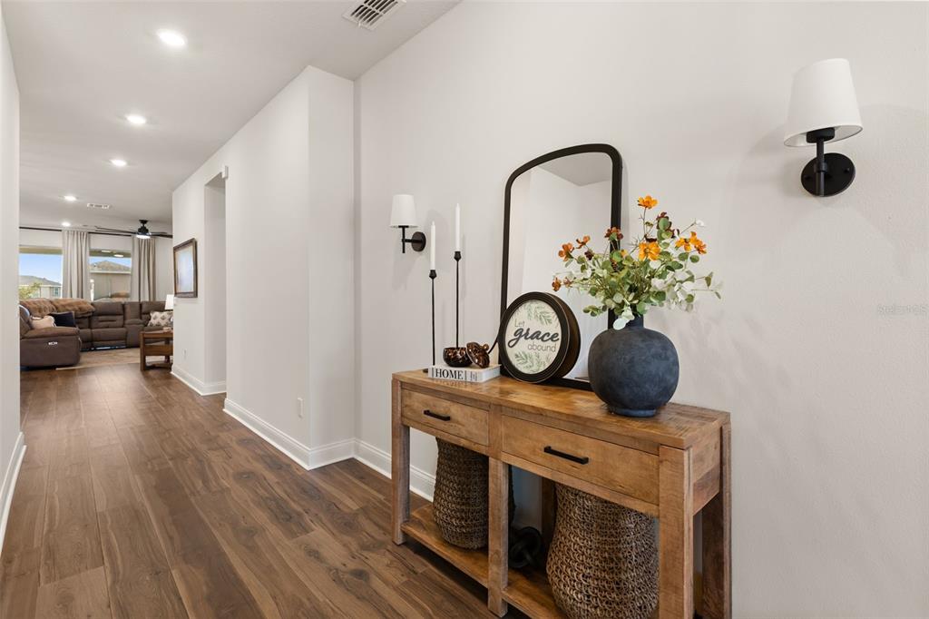 A wooden console table with decor sits in a hallway with wood-look flooring — 16974 CEDAR VALLEY CIRCLE, CLERMONT, FL