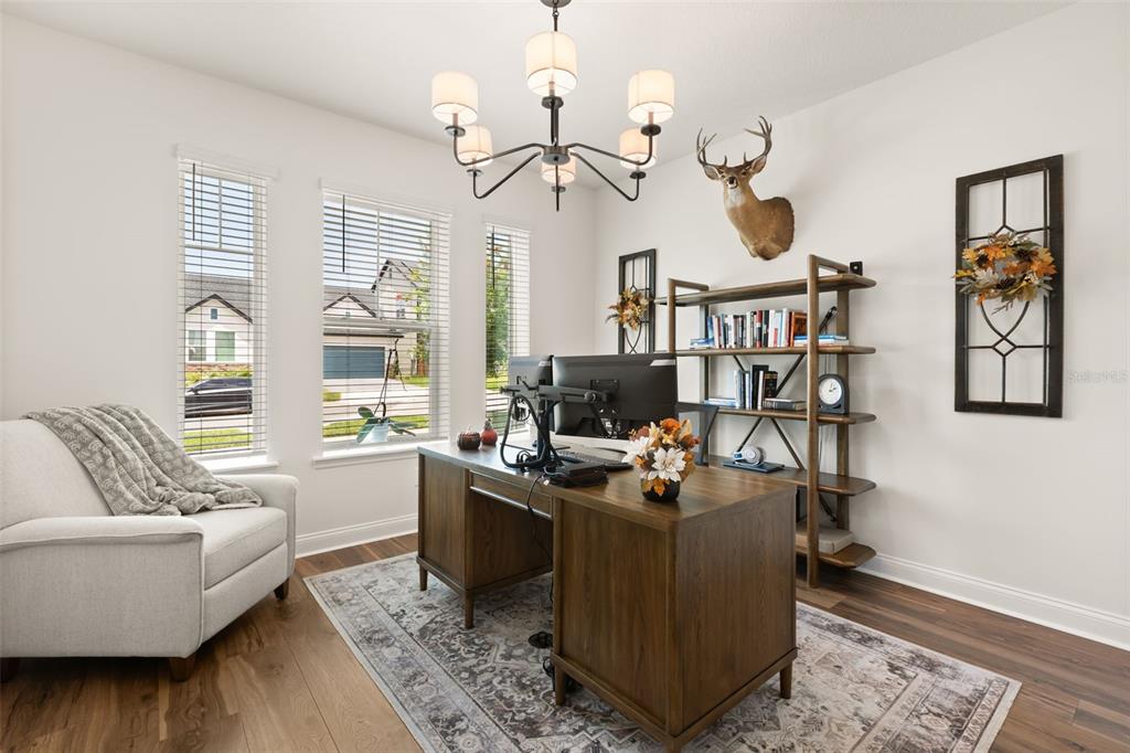 A home office features a wooden desk, a bookshelf, a deer mount, and a chandelier — 16974 CEDAR VALLEY CIRCLE, CLERMONT, FL