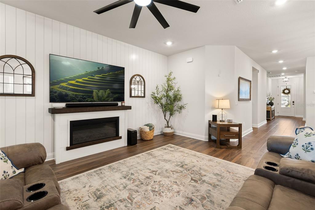 A living room features a fireplace with a mounted television, wood flooring, and white walls — 16974 CEDAR VALLEY CIRCLE, CLERMONT, FL