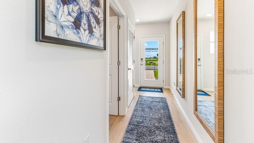 A hallway features light wood flooring, a blue runner rug, and two large wall mirrors — 1834 HAMMOCK TRACE DRIVE, PARRISH, FL