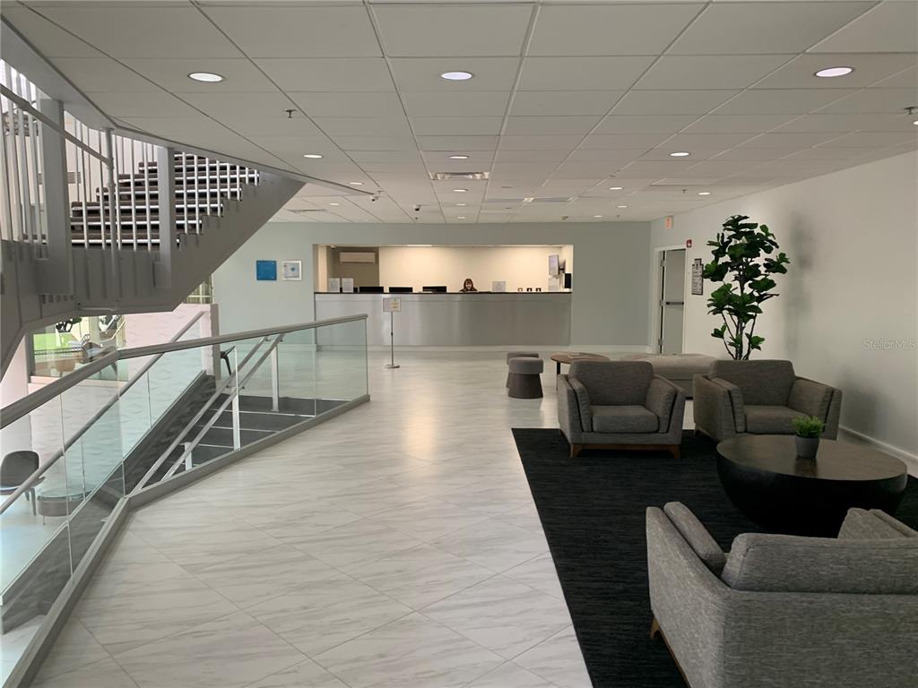 A modern office lobby features a reception desk, a staircase, and a seating area — 151 E WASHINGTON STREET UNIT 209, ORLANDO, FL