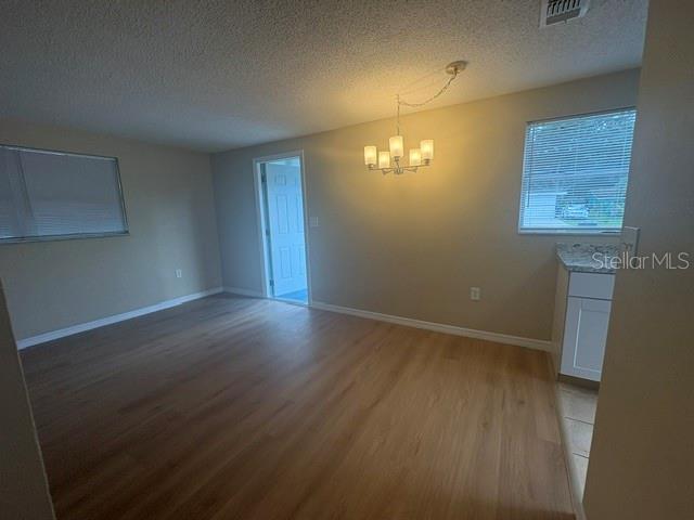 An empty dining area features light wood-look flooring, a chandelier, and a doorway to another room — 3021 OAKLAWN AVENUE UNIT A, LARGO, FL
