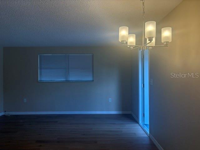 A dining area features dark wood-look flooring, a modern chandelier, and a window with blinds — 3021 OAKLAWN AVENUE UNIT A, LARGO, FL