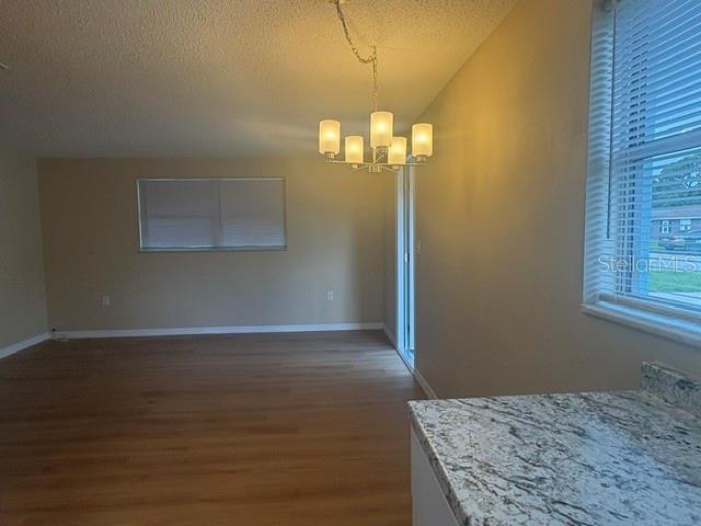An interior view shows a dining area with wood-look flooring, a chandelier, and granite countertops — 3021 OAKLAWN AVENUE UNIT A, LARGO, FL