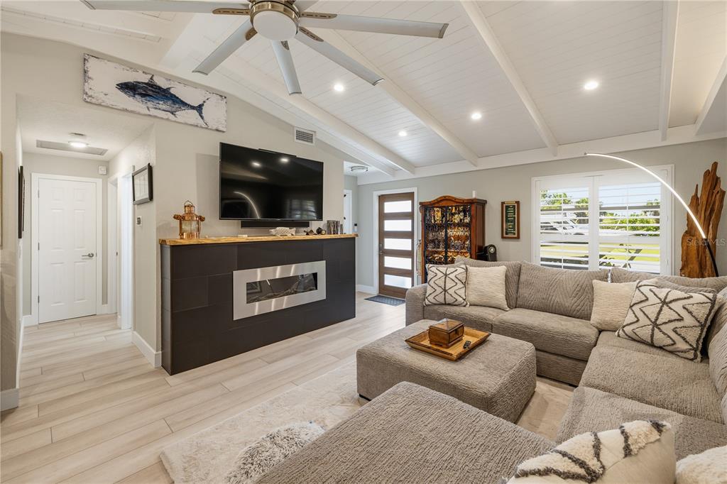 A living room features a fireplace, a sectional sofa, and a vaulted ceiling with beams — 19154 NEW HAVEN COURT, PORT CHARLOTTE, FL