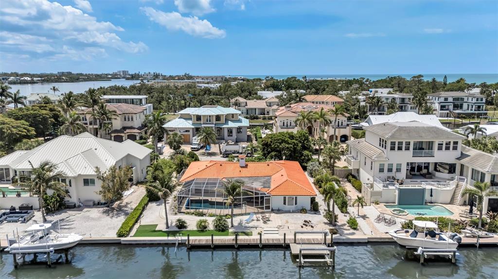An aerial view shows a waterfront house with a red-tiled roof and a boat dock — 617 ROUNTREE DRIVE, LONGBOAT KEY, FL