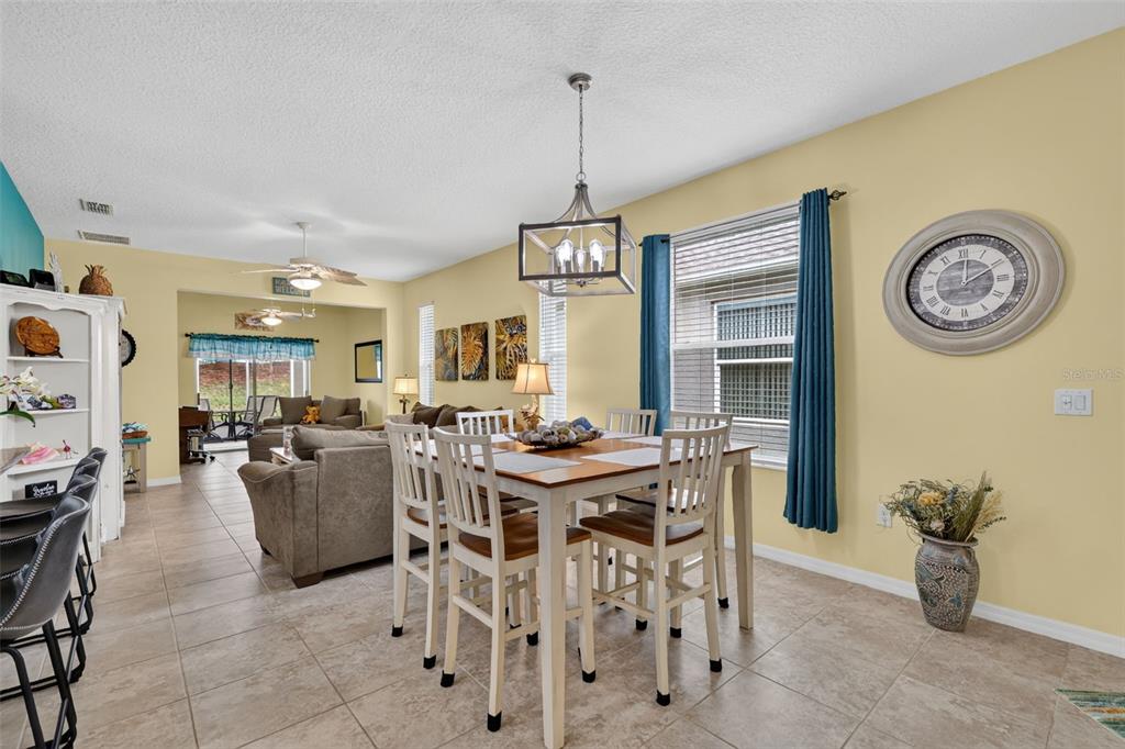 A dining area with a wooden table and chairs sits adjacent to a living room — 26951 WHITE PLAINS WAY, LEESBURG, FL