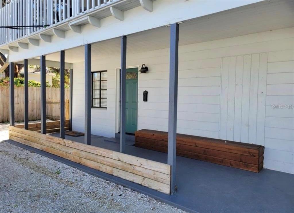 A covered porch features a teal front door, dark wooden bench, and gray support posts — 330 20TH AVENUE S UNIT LOWER, ST PETERSBURG, FL