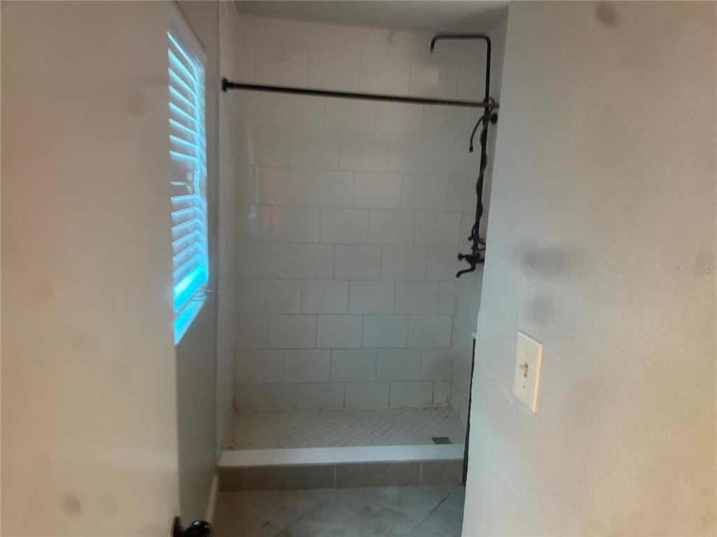 A walk-in shower features white subway tile walls, a tiled floor, and a black rod — 330 20TH AVENUE S UNIT LOWER, ST PETERSBURG, FL