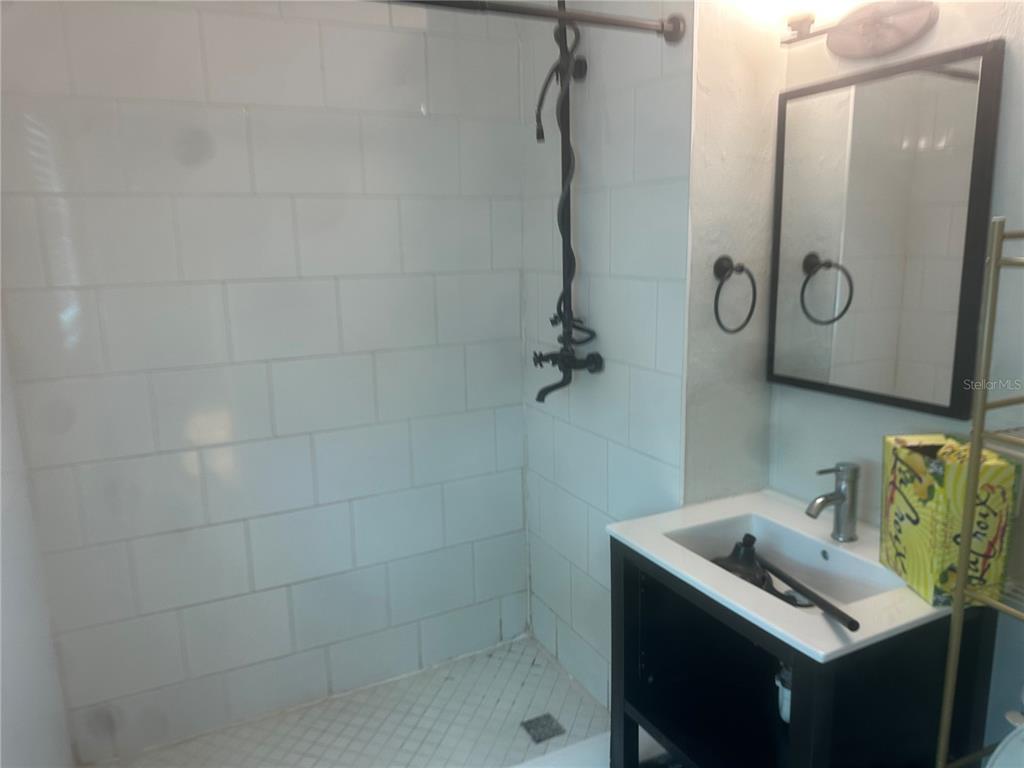 A bathroom features a tiled walk-in shower, a black vanity, and a wall-mounted mirror — 330 20TH AVENUE S UNIT LOWER, ST PETERSBURG, FL