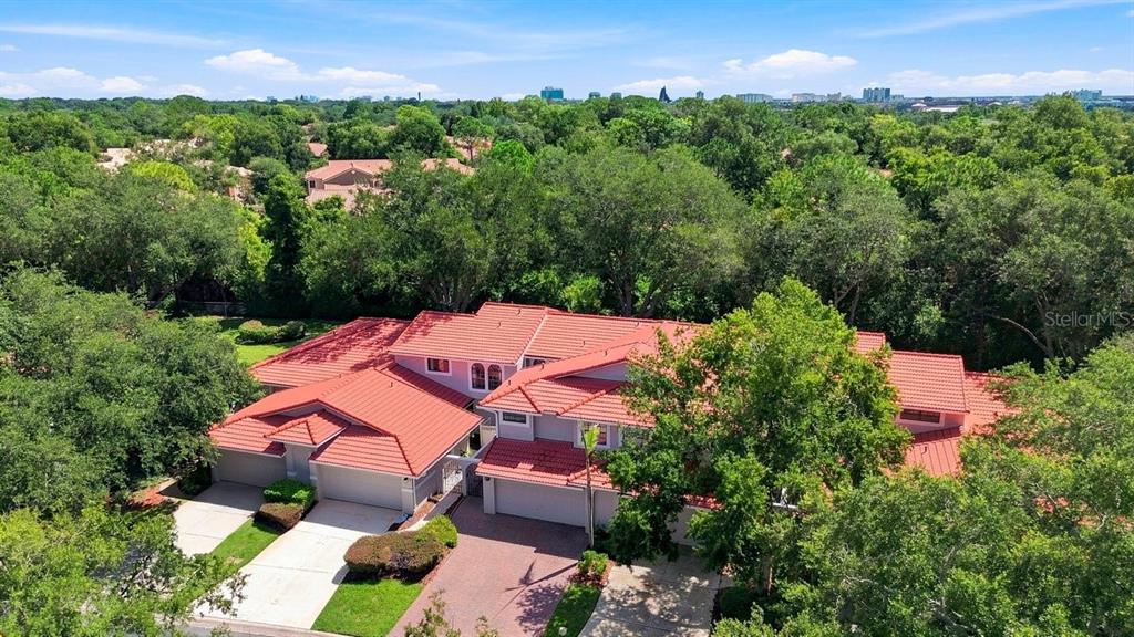 An aerial view of a multi-car garage home with a red tile roof and trees — 7537 FENWICK COVE LANE, ORLANDO, FL