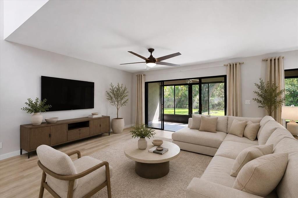 A bright living room features a sectional sofa, a television, and sliding glass doors to outdoors — 7537 FENWICK COVE LANE, ORLANDO, FL