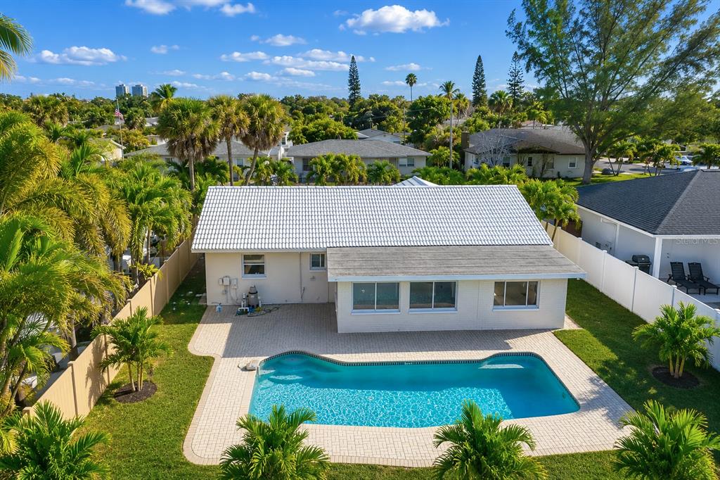 An aerial view of a single-story house with a white roof and a backyard pool — 455 81ST AVENUE, ST PETE BEACH, FL