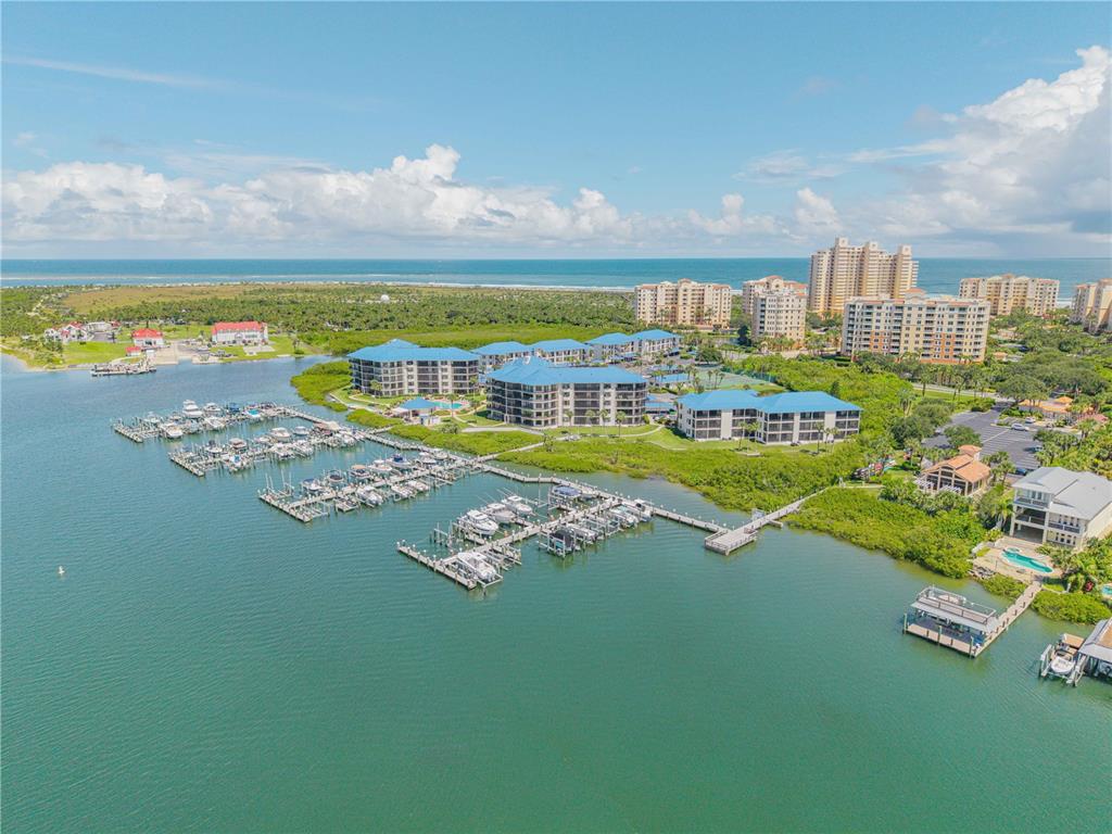 An aerial view shows a marina with docked boats next to multi-story waterfront residential buildings — 0 PENINSULA UNIT C35, NEW SMYRNA BEACH, FL
