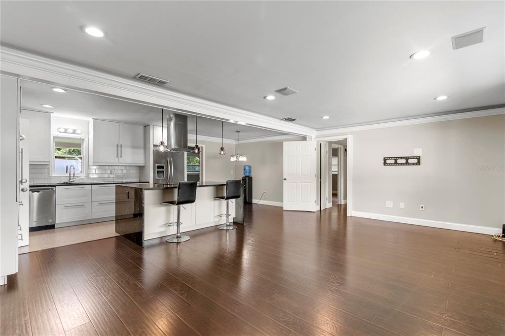 A kitchen with white cabinets and a dark island opens into a spacious living area — 1009 WOODLEY ROAD, CLEARWATER, FL