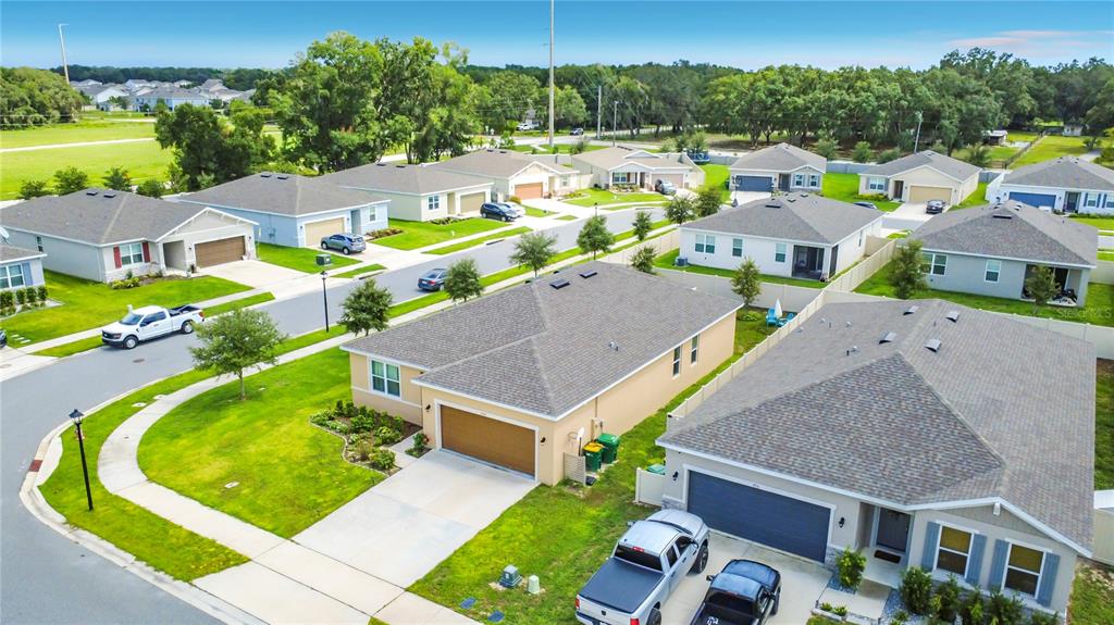 An aerial view shows several suburban houses with driveways, lawns, and parked vehicles — 3947 MAYHILL LOOP, EUSTIS, FL