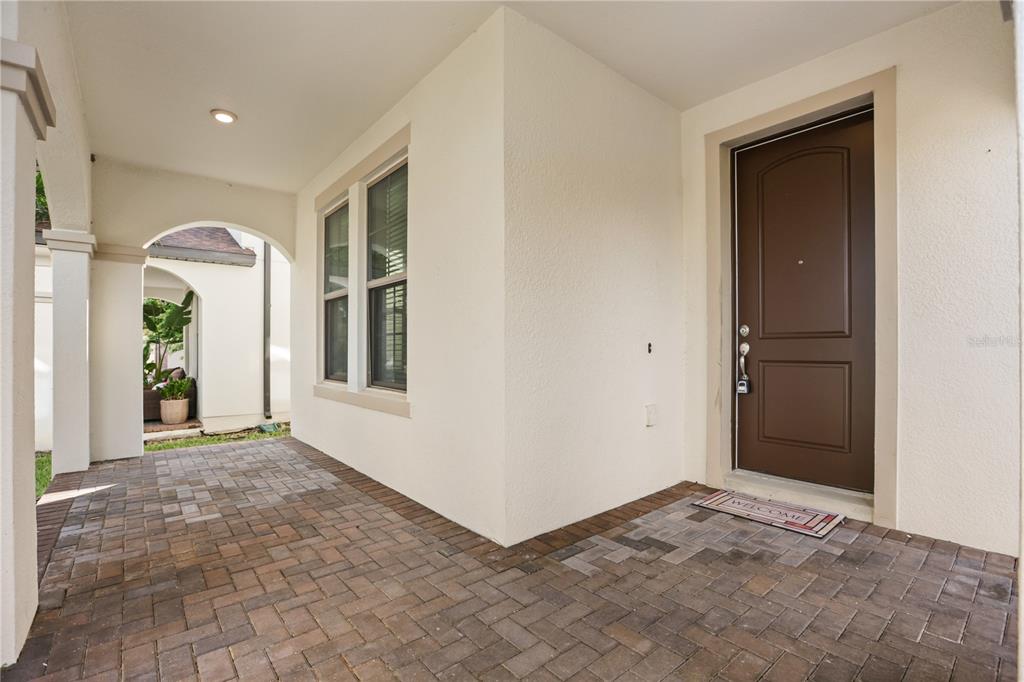 A covered front porch with brick pavers leads to a brown front door — 8278 PROCIDA ISLE LANE, WINDERMERE, FL