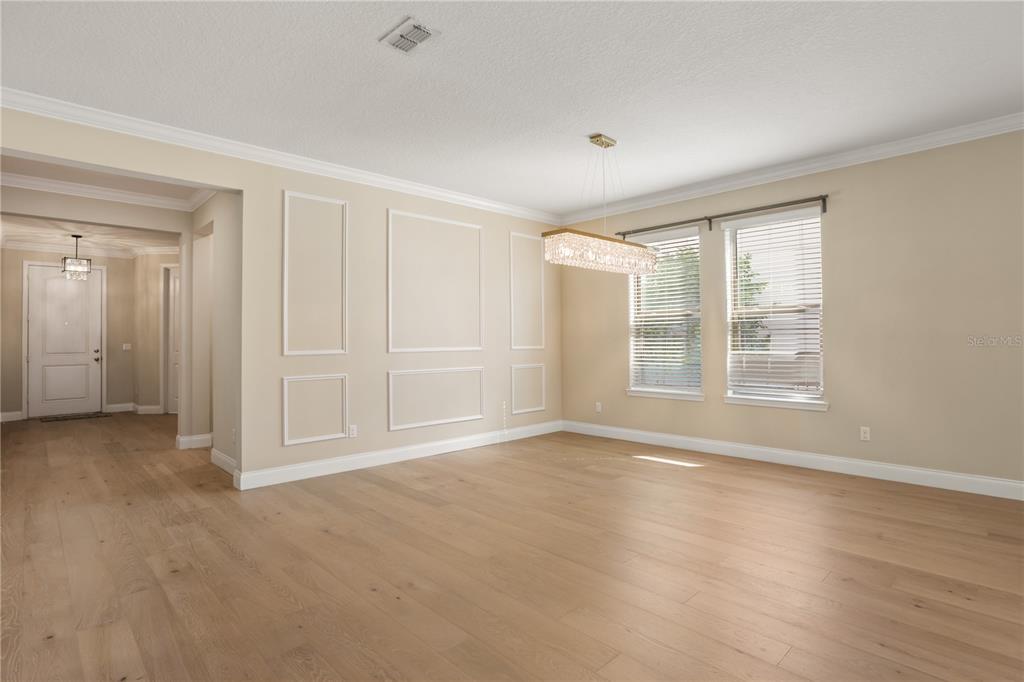 An empty dining room features light wood flooring, wall molding, and a rectangular crystal chandelier — 8278 PROCIDA ISLE LANE, WINDERMERE, FL