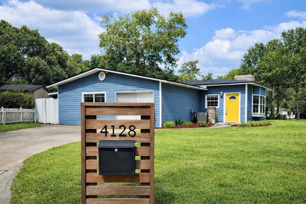 A blue single-story house with a yellow front door and a wooden mailbox post — 4128 ARCOT CIRCLE, JACKSONVILLE, FL