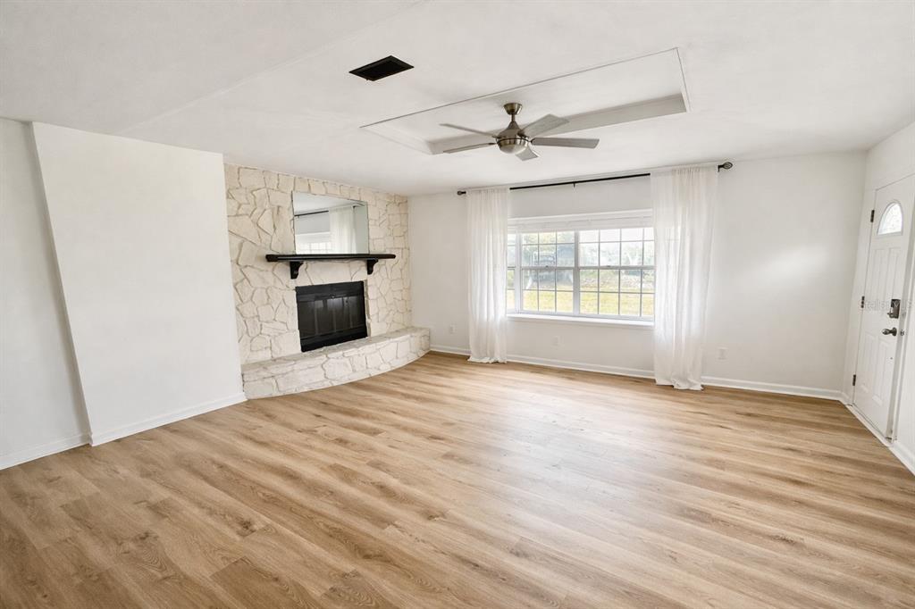 A living room features light wood-look flooring, a white stone fireplace, and a ceiling fan — 4128 ARCOT CIRCLE, JACKSONVILLE, FL
