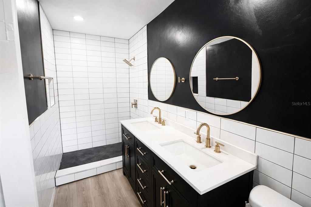A modern bathroom features a double vanity, black walls, and a white tiled walk-in shower — 4128 ARCOT CIRCLE, JACKSONVILLE, FL
