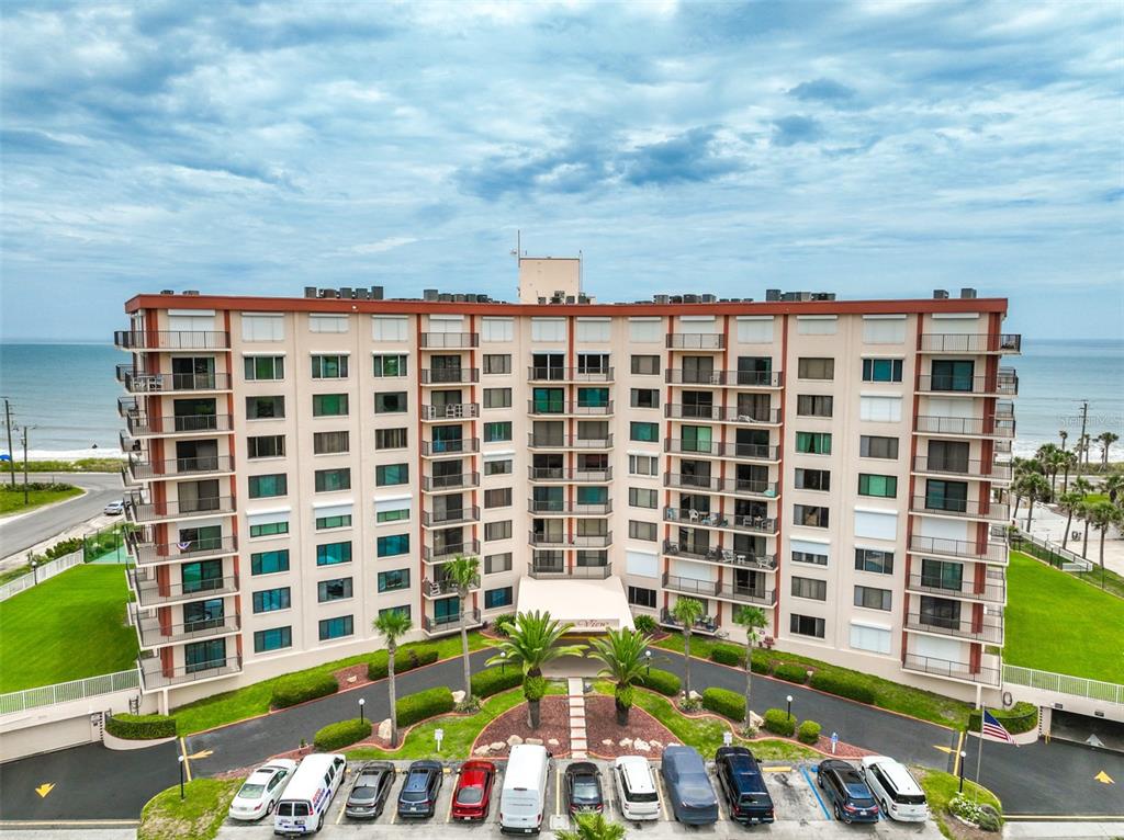 An aerial view shows a multi-story apartment building with balconies, a parking lot, and landscaping — 3600 S OCEAN SHORE BOULEVARD UNIT 222, FLAGLER BEACH, FL