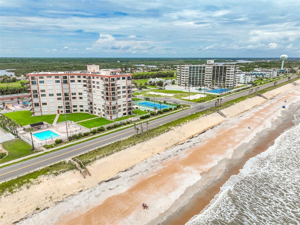 An aerial view shows two beachfront apartment buildings, a road, and a sandy beach — 3600 S OCEAN SHORE BOULEVARD UNIT 222, FLAGLER BEACH, FL