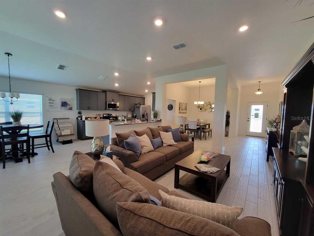 An open-concept living room and kitchen area with neutral tile flooring and brown furniture — 4493 SW 91ST LANE ROAD, OCALA, FL