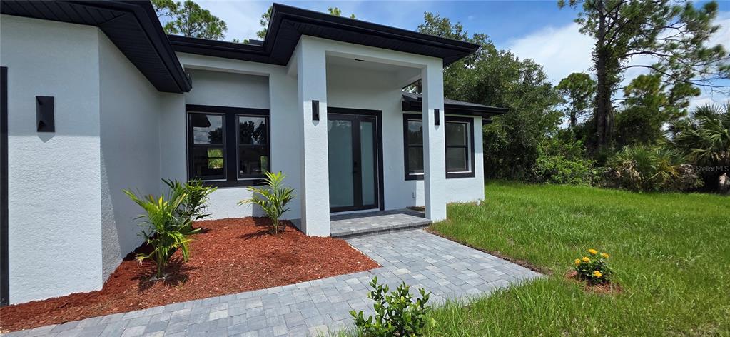 A modern white house exterior features a paved walkway leading to a double front door — 1267 HENNING STREET, NORTH PORT, FL