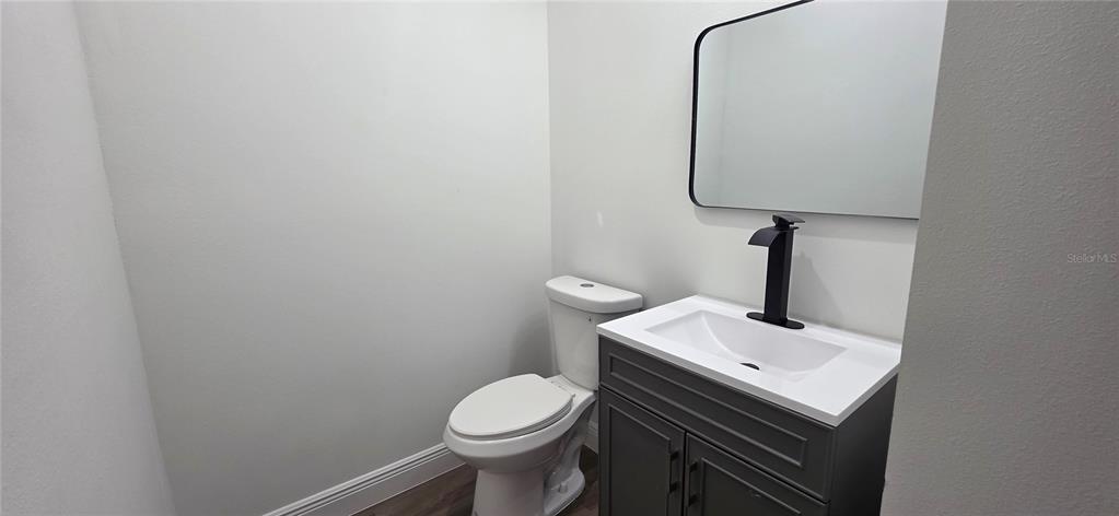 A small bathroom features a gray vanity, a white sink, a black faucet, and a toilet — 1267 HENNING STREET, NORTH PORT, FL