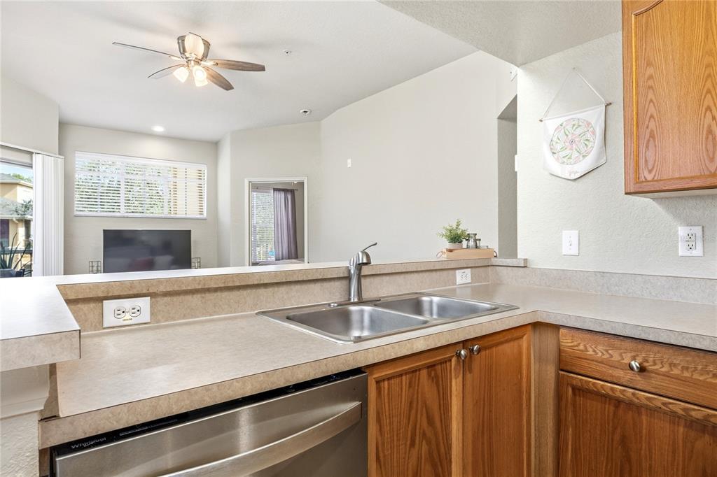 A living room features a white sofa, wood-look flooring, a television console, and a balcony — 5125 PALM SPRINGS BOULEVARD UNIT 1204, TAMPA, FL