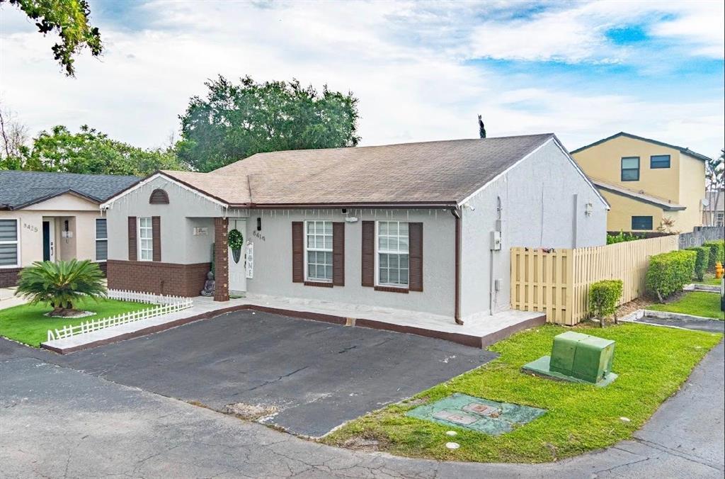 A single-story house with a gray stucco exterior, brown shutters, and an asphalt driveway — 8419 NW 193RD LN, HIALEAH, FL