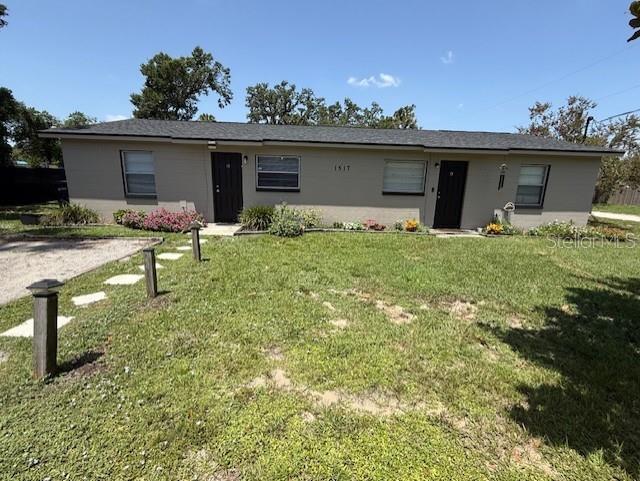 A single-story duplex with a gray exterior, two front doors, and a grassy front yard — 1517 S TAYLOR ROAD, SEFFNER, FL