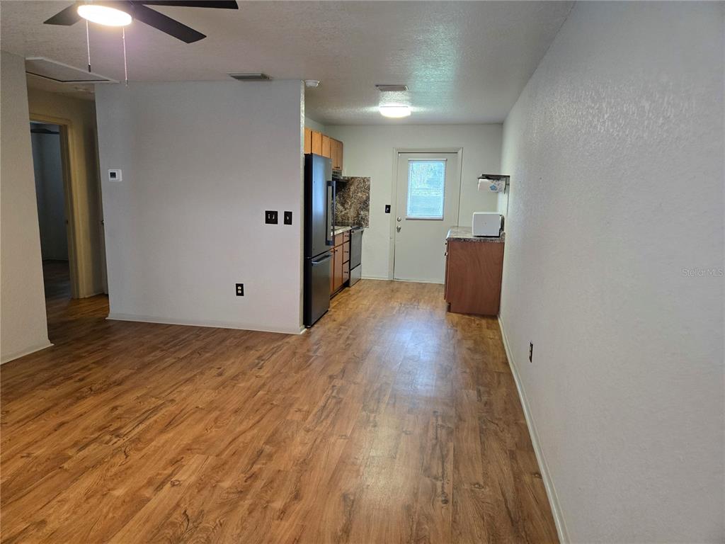 A kitchen with wood-look flooring, wood cabinets, a black refrigerator, and a back door — 1517 S TAYLOR ROAD, SEFFNER, FL
